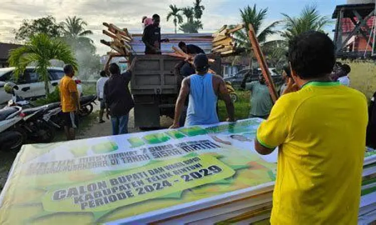 Aksi Relawan Kampanye Relawan bergotong royong memasang alat peraga kampanye